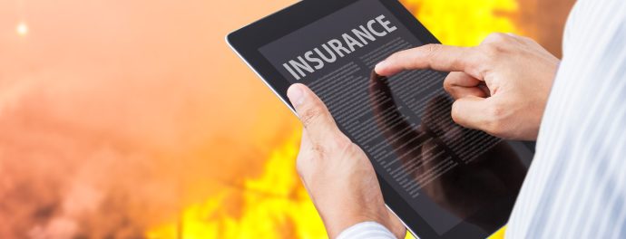 Man pointing at insurance wording on tablet with fire background